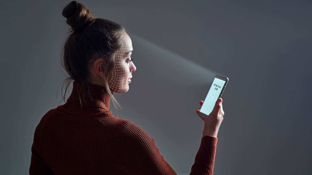 Mulher tendo o rosto escaneado por celular, aludindo ao liveness.