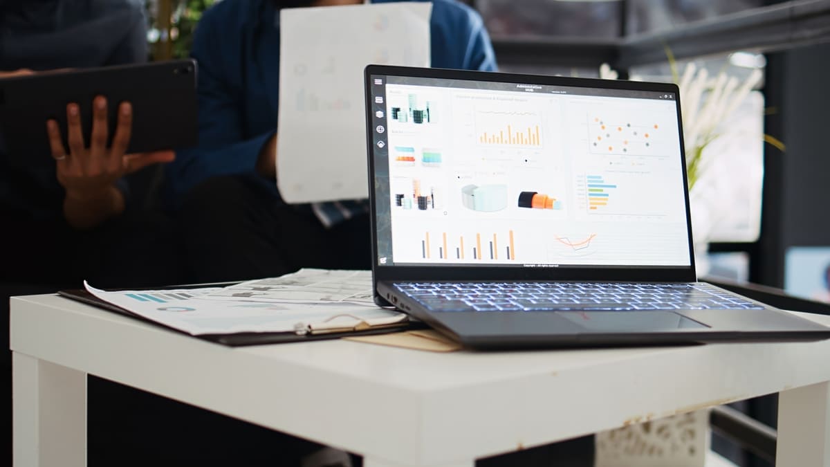 Notebook sobre a mesa e exibindo em sua tela gráficos e demais dados sobre clientes, representando o customer data platform.