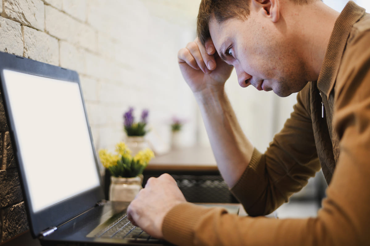 Homem cabisbaixo tentando usar o computador durante o apagão cibernético 2024.